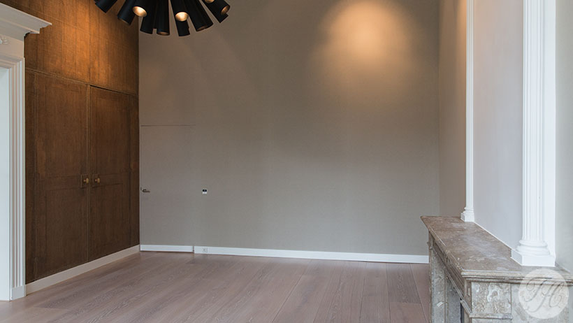 Stoffen wandbespanning blind afgewerkt en klassieke betengeling naast elkaar in herenhuis