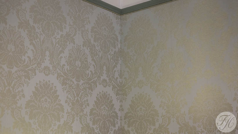 Muur bespannen met een damast stoffen wandbespanning en is afgewerkt met koord